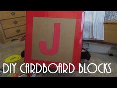 a diy cardboard block with the letter j on it in front of a bed