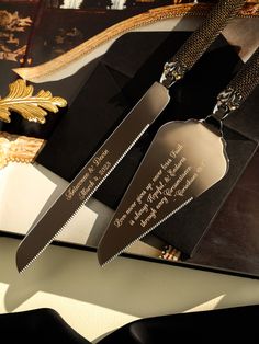 two knifes are sitting on top of a black and white book with gold trimming