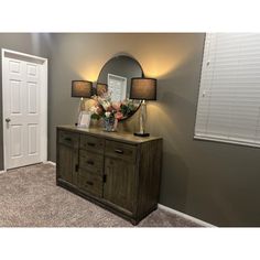 a room with a dresser, mirror and two lamps on top of the dressers