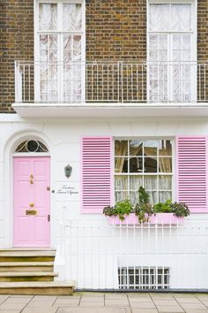 a pink door and window in front of a white house