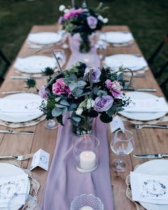 the table is set with plates, silverware and flowers