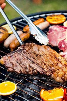 a person is grilling meat and vegetables on a bbq with two tongs