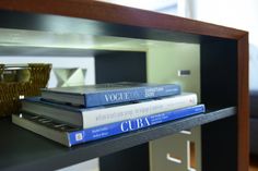 three books are stacked on top of each other in front of a glass shelf with a basket next to it