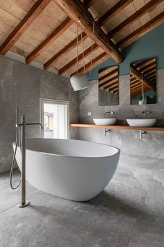 a large white bath tub sitting inside of a bathroom next to two sinks and mirrors