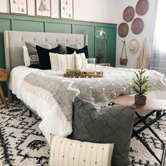 a large bed sitting in a bedroom next to a table with a potted plant on it