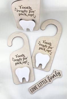 three tooth shaped wooden tags with words on them