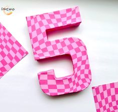 the number five is made out of pink and white checkerboard paper with scissors next to it