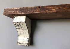 a close up of a piece of wood on a wall with a wooden shelf in the background