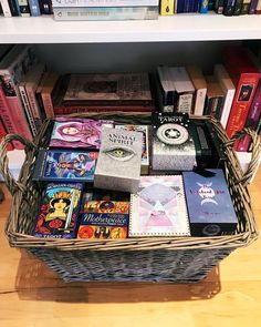 a basket filled with books sitting on top of a wooden floor next to a book shelf