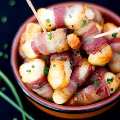 bacon wrapped potatoes in a bowl with toothpicks sticking out of the top and green onions on the side