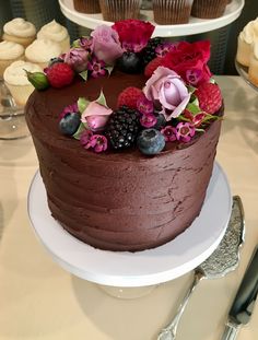 a chocolate cake with fresh berries and flowers on top