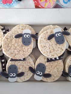 some cupcakes with sheep on them are in a box and ready to be eaten