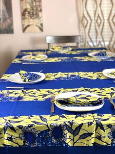 blue and yellow table cloths with white plates on them in a dining room setting