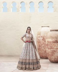 a woman standing in front of two vases wearing a bridal dress and veil