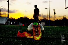 a soccer ball sitting on top of a field next to a man standing in the background