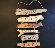 three driftwood signs hanging on a black wall