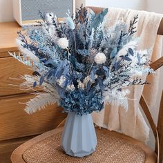 a vase filled with blue and white flowers on top of a wooden chair