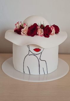 a white hat with red and pink flowers on it sitting on top of a wooden table