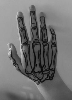 a black and white photo of a hand with bones painted on it's palm