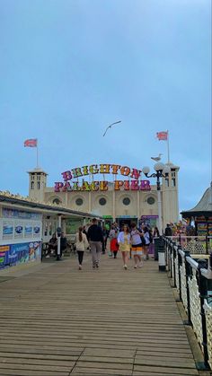 people are walking on the boardwalk at an amusement park