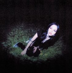 a woman sitting in the grass with her hands on her knees and eyes closed, looking at the camera