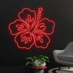 a neon sign that is on the wall next to a chair and potted plant