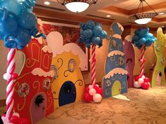 there are many decorations on the tables in this room that is decorated with blue, red and yellow balloons