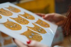 a woman holding a box with gold foiled cats on it's front and side