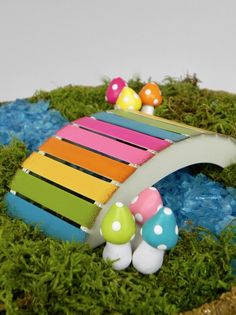 a small wooden bridge with colorful decorations on it's sides and moss growing around