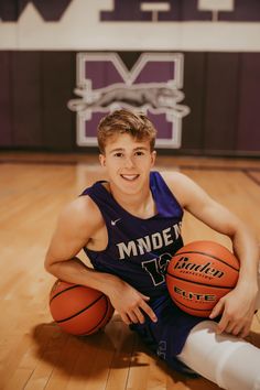 a young man sitting on the floor holding a basketball