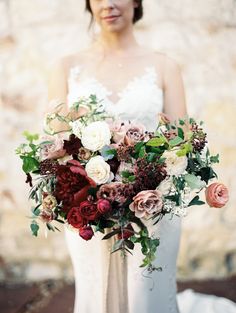 a bride holding a bouquet of flowers in her hands and looking at the camera with an expression on her face