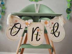 a baby highchair decorated with flowers and the number one on it's banner