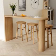 a table with two stools and a clock on the wall above it in a kitchen