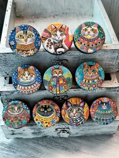 there are many colorful cat magnets on the wooden shelf in front of each other