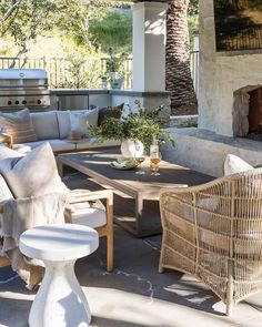 an outdoor living area with wicker furniture and a fire place in the back ground