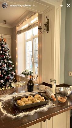 a christmas tree is in the corner of a kitchen with cookies and other foods on the counter