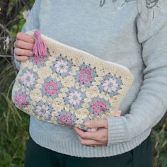 a woman holding a crocheted purse in front of her face with flowers on it