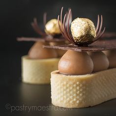 some kind of dessert with chocolate and gold leaf decorations on it's top, sitting on a black surface