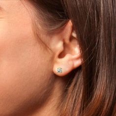 a close up of a person's ear wearing a pair of diamond studs