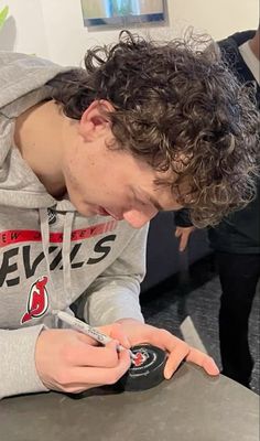 a young man looking at his cell phone while sitting at a table in front of him