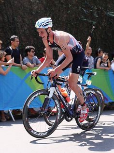 a man riding a bike down a street next to a group of people watching him