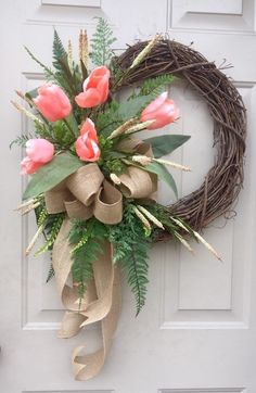 a wreath with pink flowers and greenery on the front door