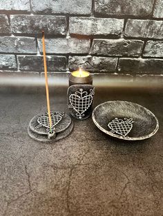 two candles are sitting next to each other on a table with plates and cups in the shape of hearts