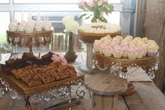 an assortment of cupcakes and pastries displayed on trays in front of a window