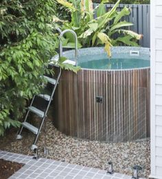 an outdoor hot tub with steps leading up to it and plants growing in the background