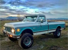 a blue and white truck parked on top of a grass covered field