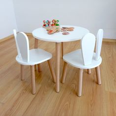 two white children's chairs sitting at a table with cookies on the table top