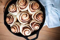 a pan filled with cinnamon rolls on top of a wooden table