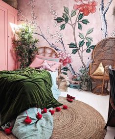 a bedroom decorated in pink and green with flowers on the wall, bedding and rugs