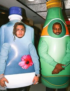 two men standing next to each other in front of giant bottles with faces on them